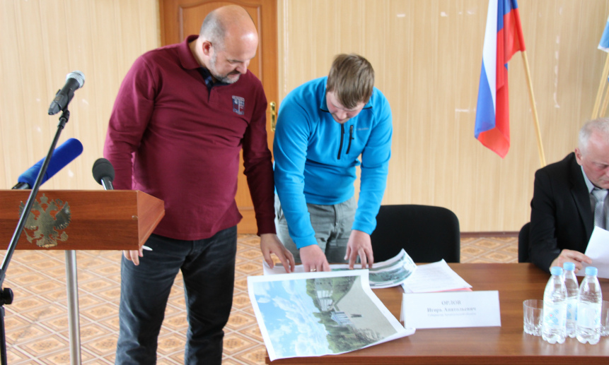 Местный активист демонстрирует Игорю Орлову планы по созданию площади на месте бывшей библиотеки.